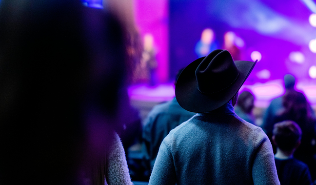 En bild på en person med cowboy-hatt som ser på en konsert